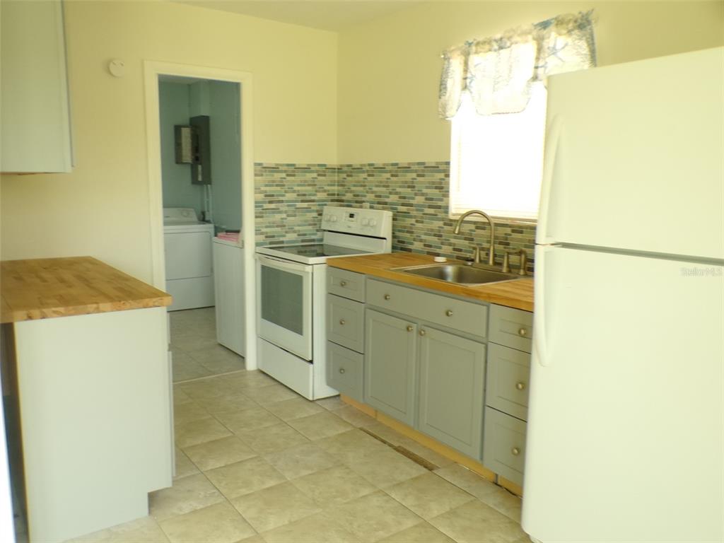 A kitchen features light-colored cabinets, a butcher block countertop, a tiled backsplash, and white appliances — 4011 GROBE STREET, NORTH PORT, FL
