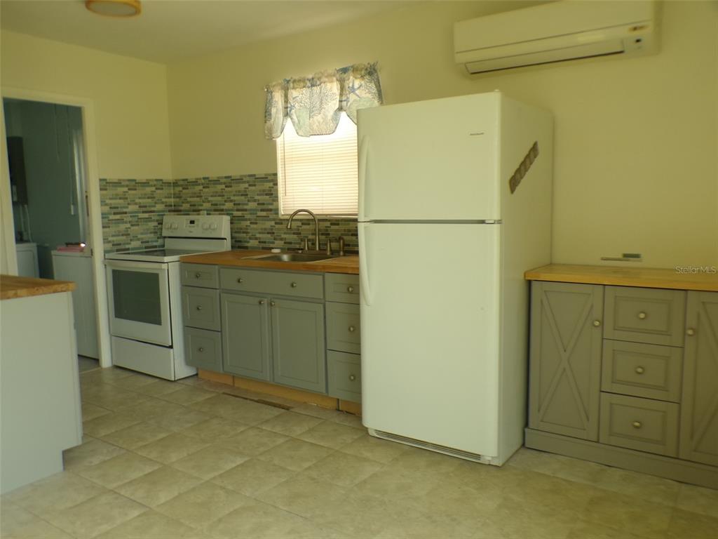 A kitchen features gray cabinets, a white refrigerator, a white stove, and a tiled backsplash — 4011 GROBE STREET, NORTH PORT, FL