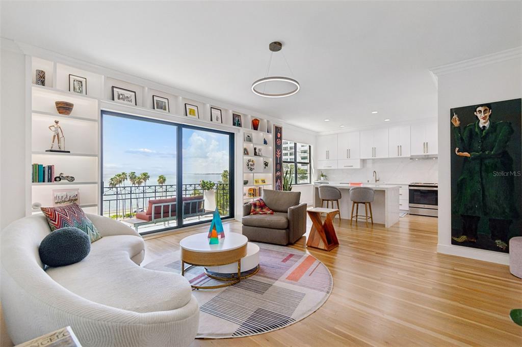 An open-concept living room and kitchen features white cabinetry, hardwood floors, and a balcony view — 2109 BAYSHORE BOULEVARD UNIT 504, TAMPA, FL