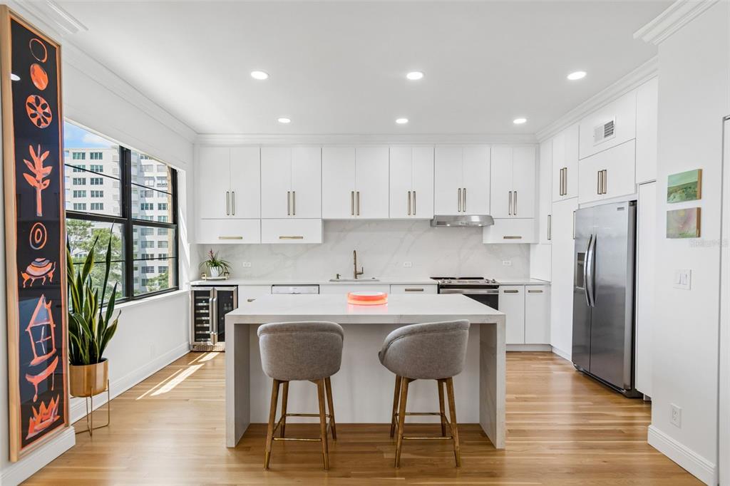 A modern kitchen features white cabinetry, a marble-topped island with two stools, and stainless appliances — 2109 BAYSHORE BOULEVARD UNIT 504, TAMPA, FL