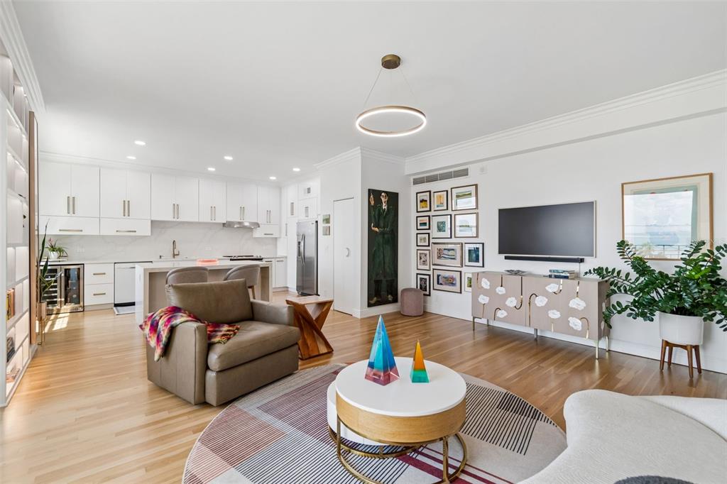 An open-concept living room and kitchen featuring white cabinetry, hardwood floors, and a modern chandelier — 2109 BAYSHORE BOULEVARD UNIT 504, TAMPA, FL