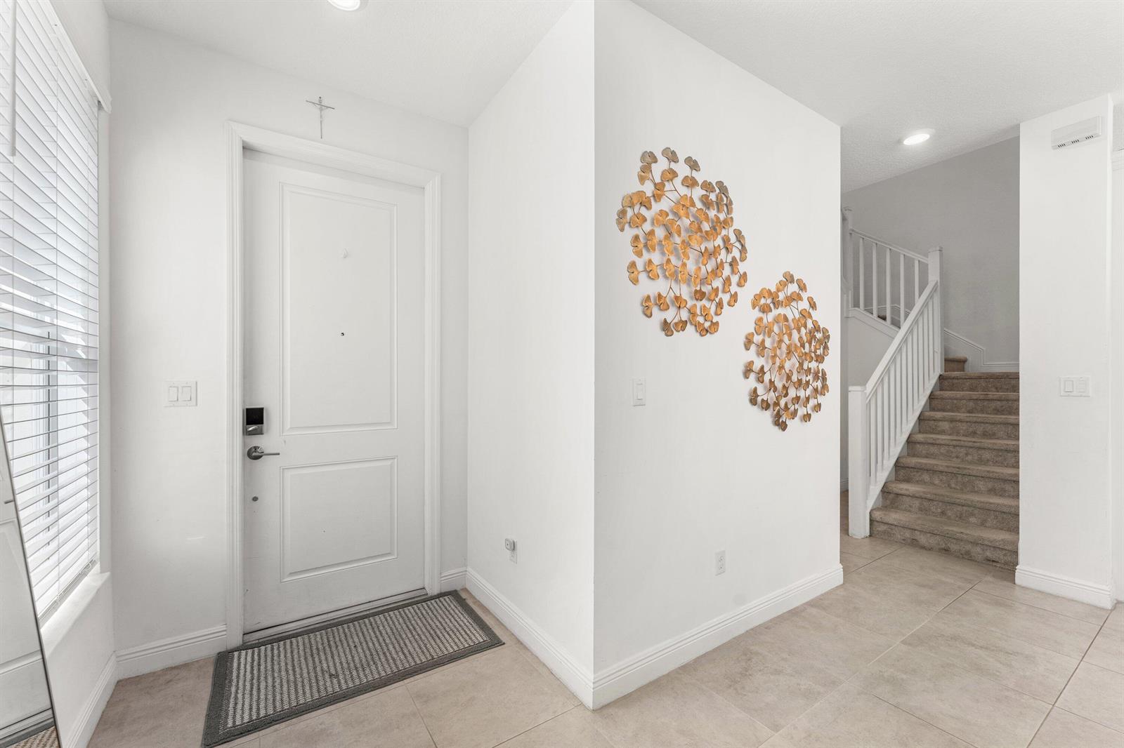 A brown front door sits on a paved porch with two wicker chairs and lanterns — 4330 Lago Drive, Deerfield Beach FL 33064, DEERFIELD BEACH, FL