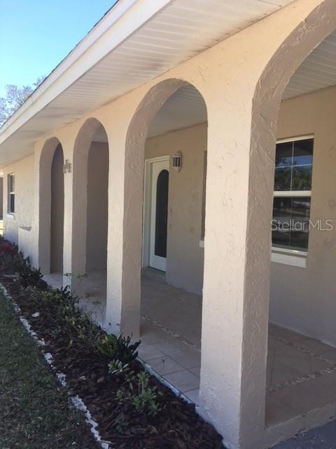A beige stucco house exterior features a covered porch with three arched support columns — 888 S WATERVIEW DRIVE, CLERMONT, FL