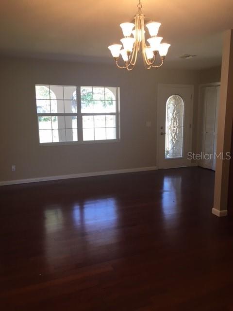 A dining room with dark hardwood floors, a chandelier, and a front door with glass — 888 S WATERVIEW DRIVE, CLERMONT, FL