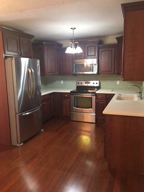 A kitchen features dark wood cabinets, stainless steel appliances, and hardwood flooring — 888 S WATERVIEW DRIVE, CLERMONT, FL