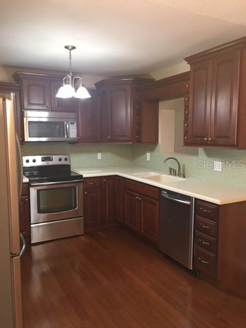 A kitchen with dark wood cabinets, stainless steel appliances, and light countertops — 888 S WATERVIEW DRIVE, CLERMONT, FL