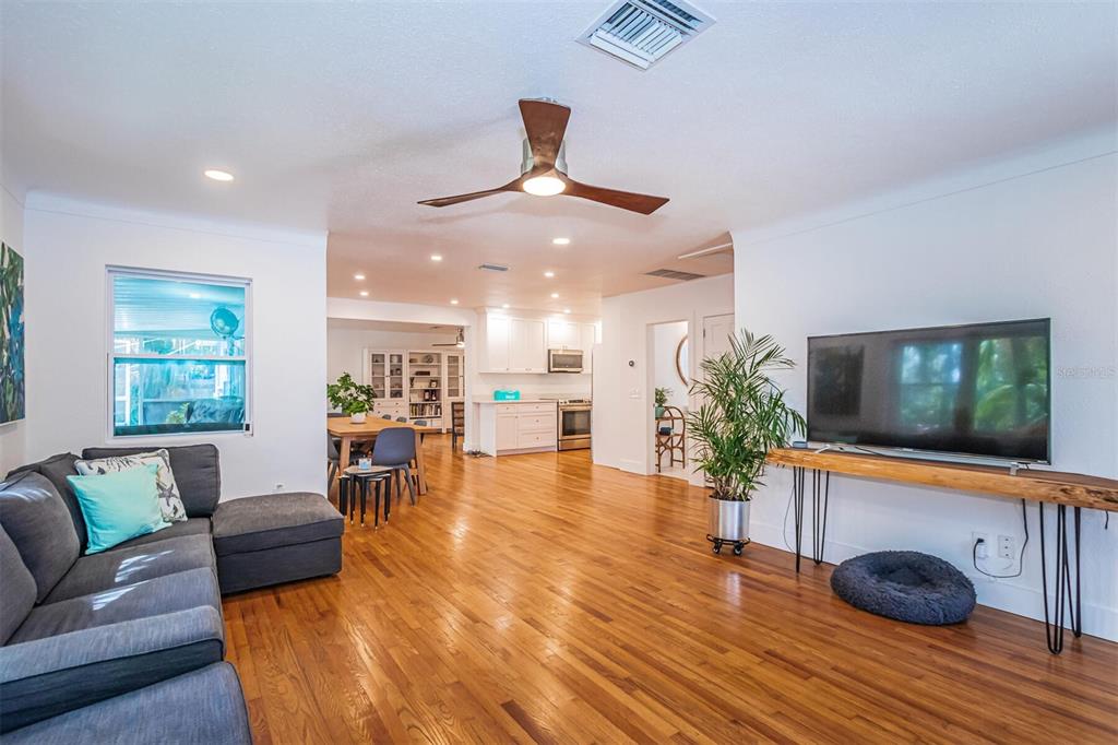 A living room with hardwood floors, a gray sectional sofa, and an open kitchen beyond — 2657 44TH STREET S, GULFPORT, FL