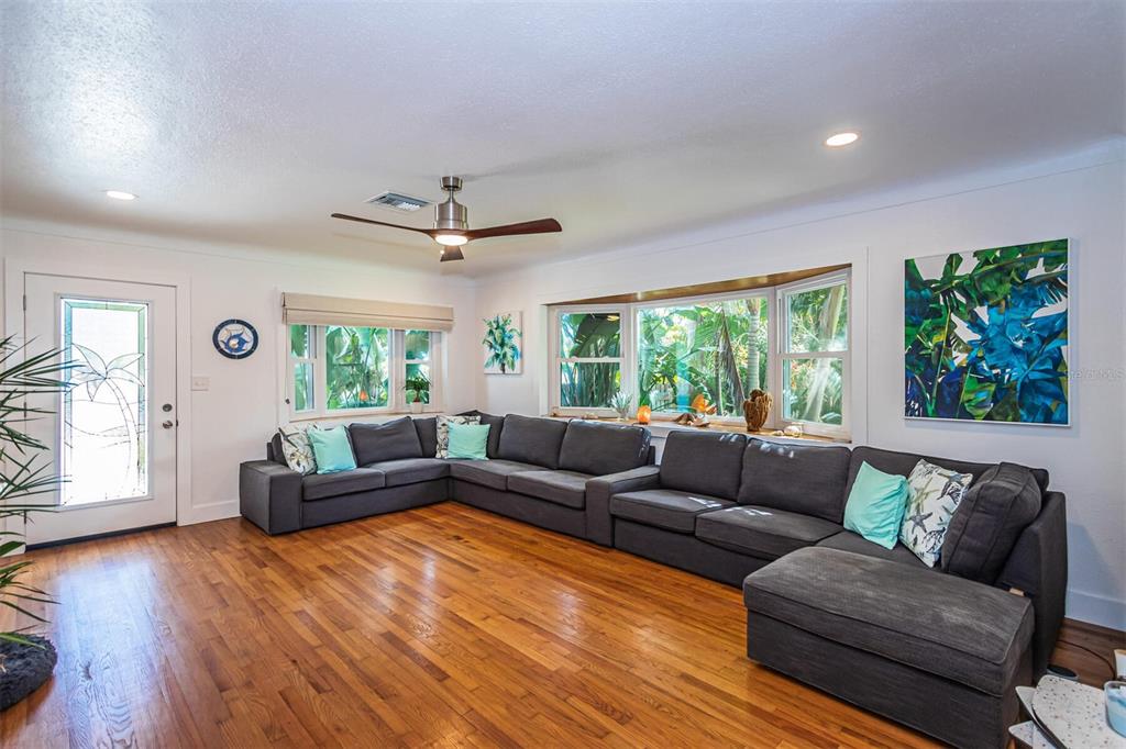 A living room features a large gray sectional sofa, hardwood floors, and a bay window — 2657 44TH STREET S, GULFPORT, FL