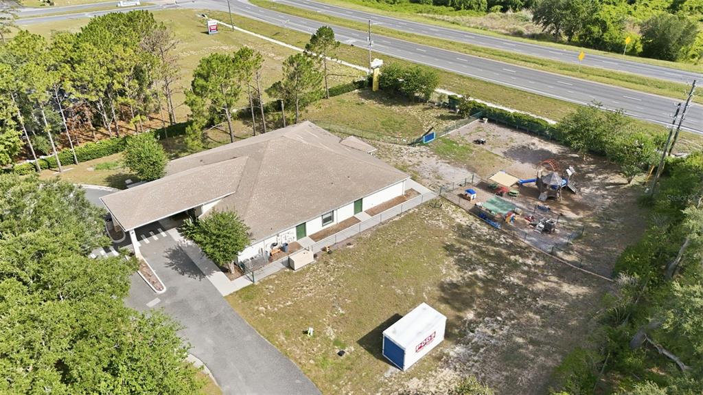 An aerial view shows a single-story building with a carport, playground, and storage container — 20540 INDEPENDENCE BOULEVARD, GROVELAND, FL