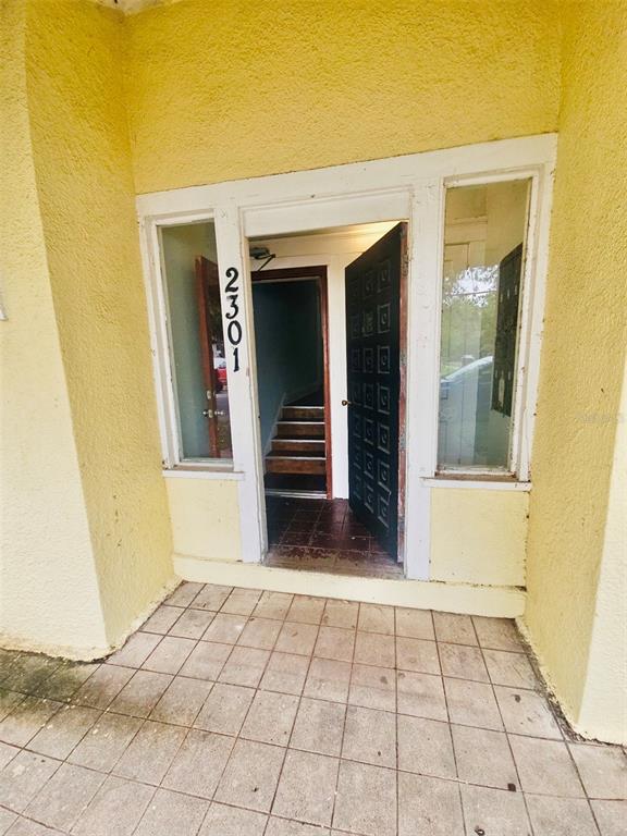 The exterior entrance features a yellow stucco wall, a tiled porch, and a glass-paneled door — 2301 N JEFFERSON STREET, TAMPA, FL