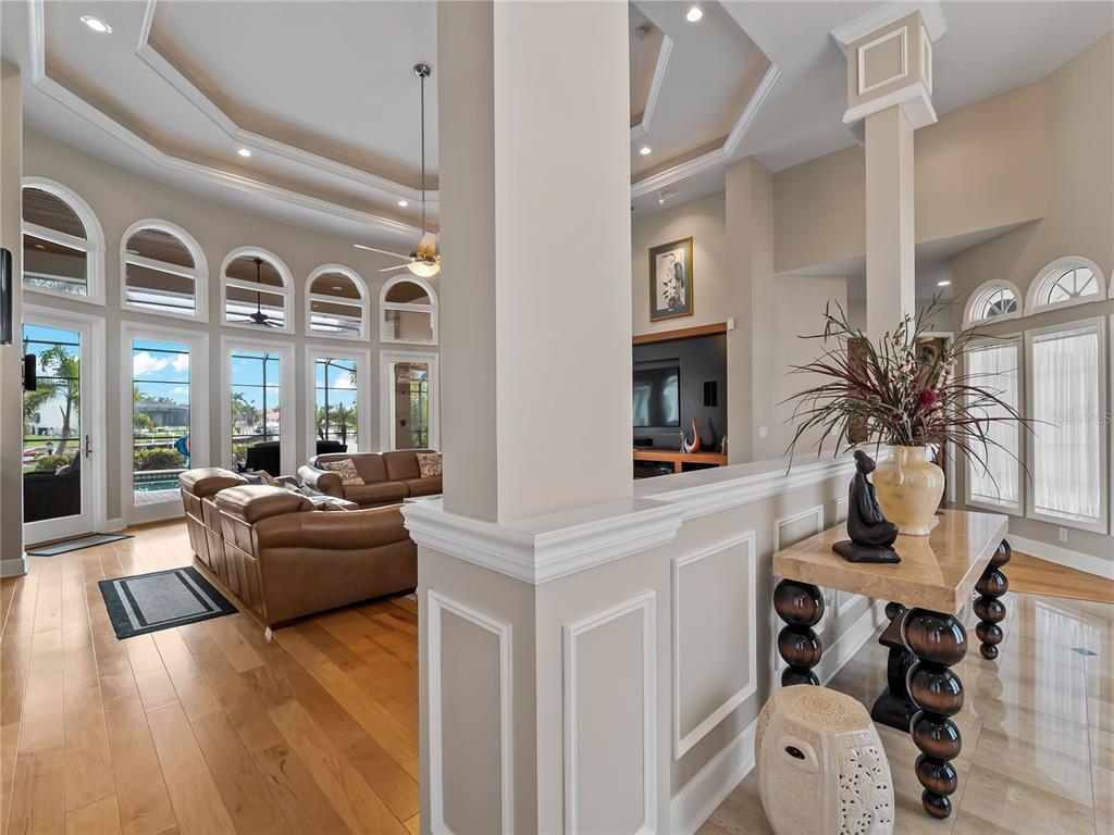 A living room with vaulted ceilings, hardwood floors, and large arched windows overlooking a pool — 1443 SURFBIRD COURT, PUNTA GORDA, FL