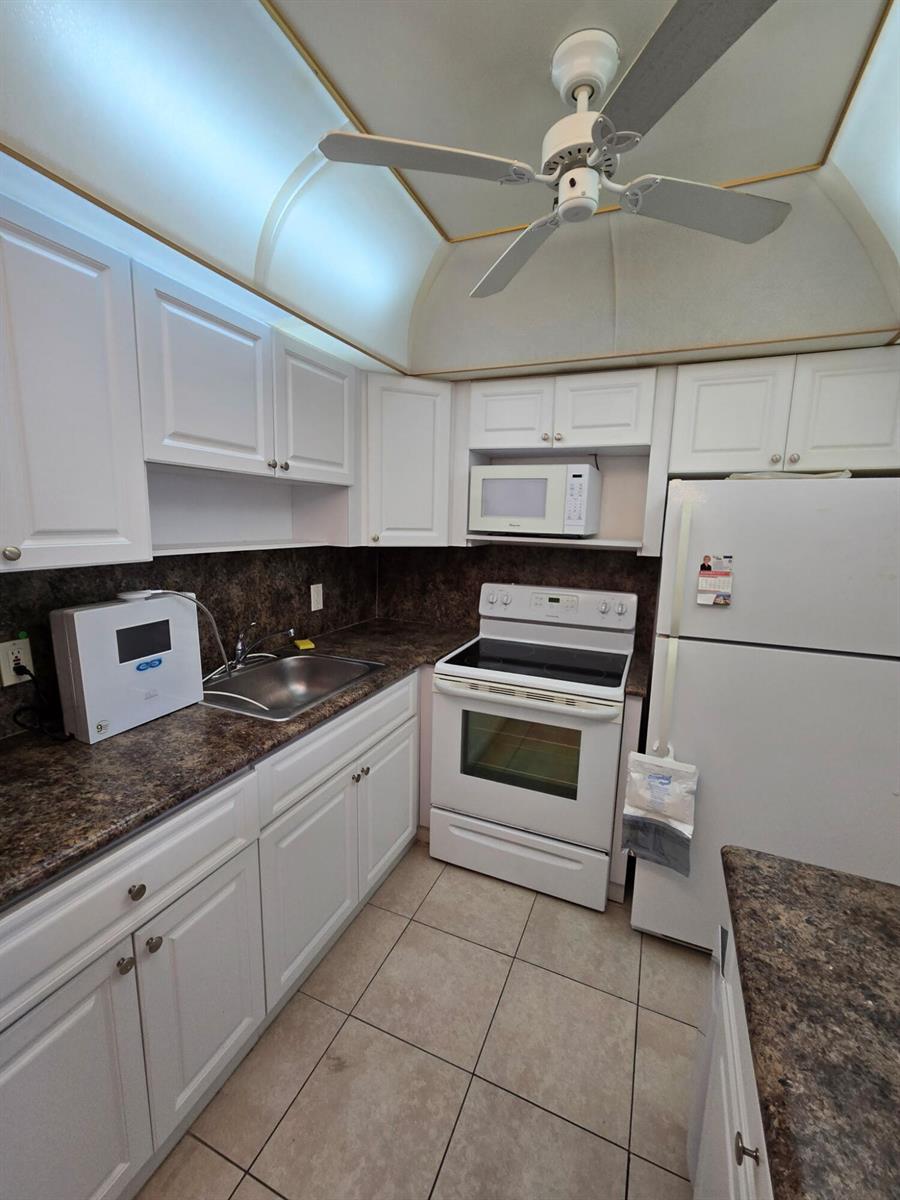 A kitchen with white cabinets, dark countertops, white appliances, and a ceiling fan — 133 Ventnor I Drive # 133, Deerfield Beach FL 33442, DEERFIELD BEACH, FL