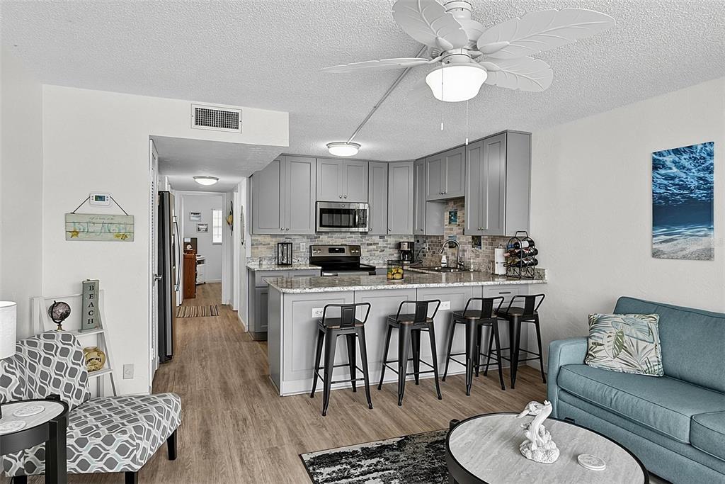A kitchen with grey cabinets and a breakfast bar opens into a living area — 1433 N ATLANTIC AVENUE UNIT 329, DAYTONA BEACH, FL