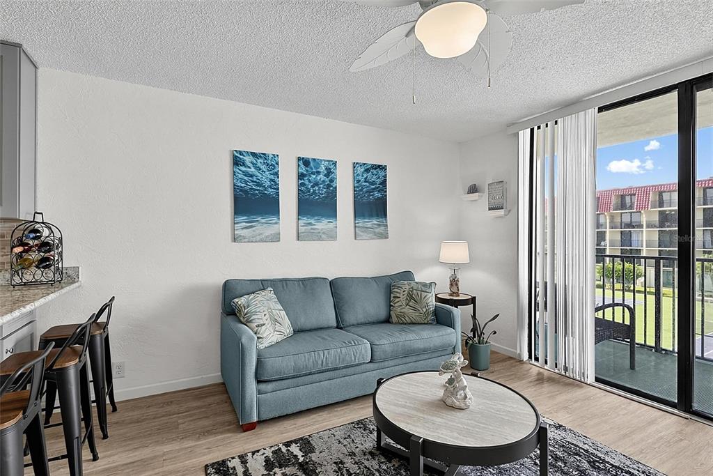 A living room features a blue sofa, a round coffee table, and a sliding glass door — 1433 N ATLANTIC AVENUE UNIT 329, DAYTONA BEACH, FL