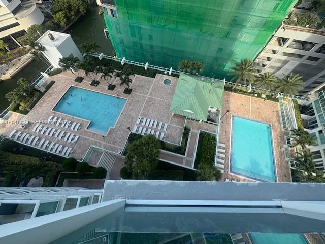 An aerial view shows two swimming pools, a green-roofed gazebo, and lounge chairs on a patio — MIAMI, FL