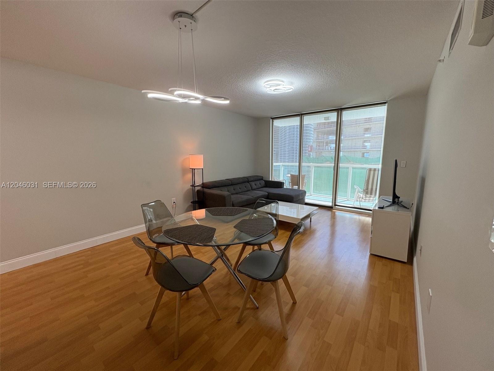 A living and dining area features wood flooring, a glass table, and a sectional sofa — MIAMI, FL