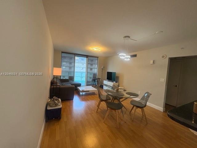 This open-concept living and dining area features wood-style flooring and floor-to-ceiling balcony windows — MIAMI, FL