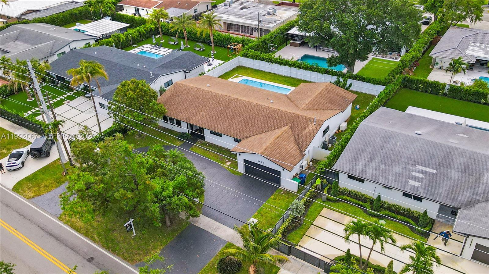 An aerial view shows a suburban house with a brown roof, pool, and paved driveway — 1850 NE 199th St, Miami FL 33179, MIAMI, FL