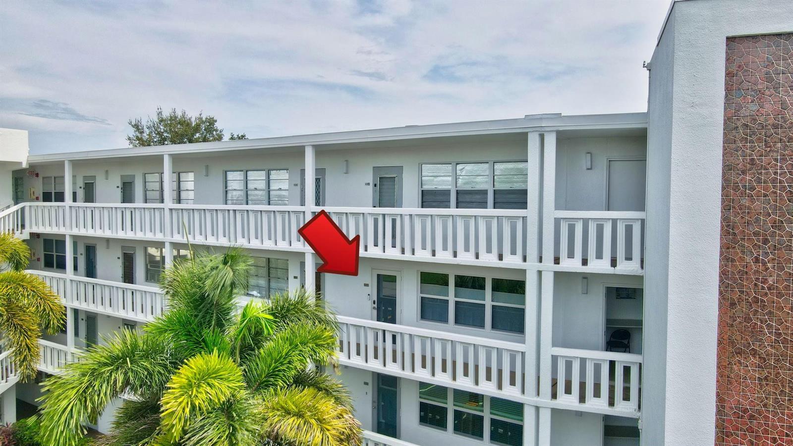 An exterior view of a multi-story apartment building with white railings and a red arrow — 3107 Cambridge # 3107, Deerfield Beach FL 33442, DEERFIELD BEACH, FL