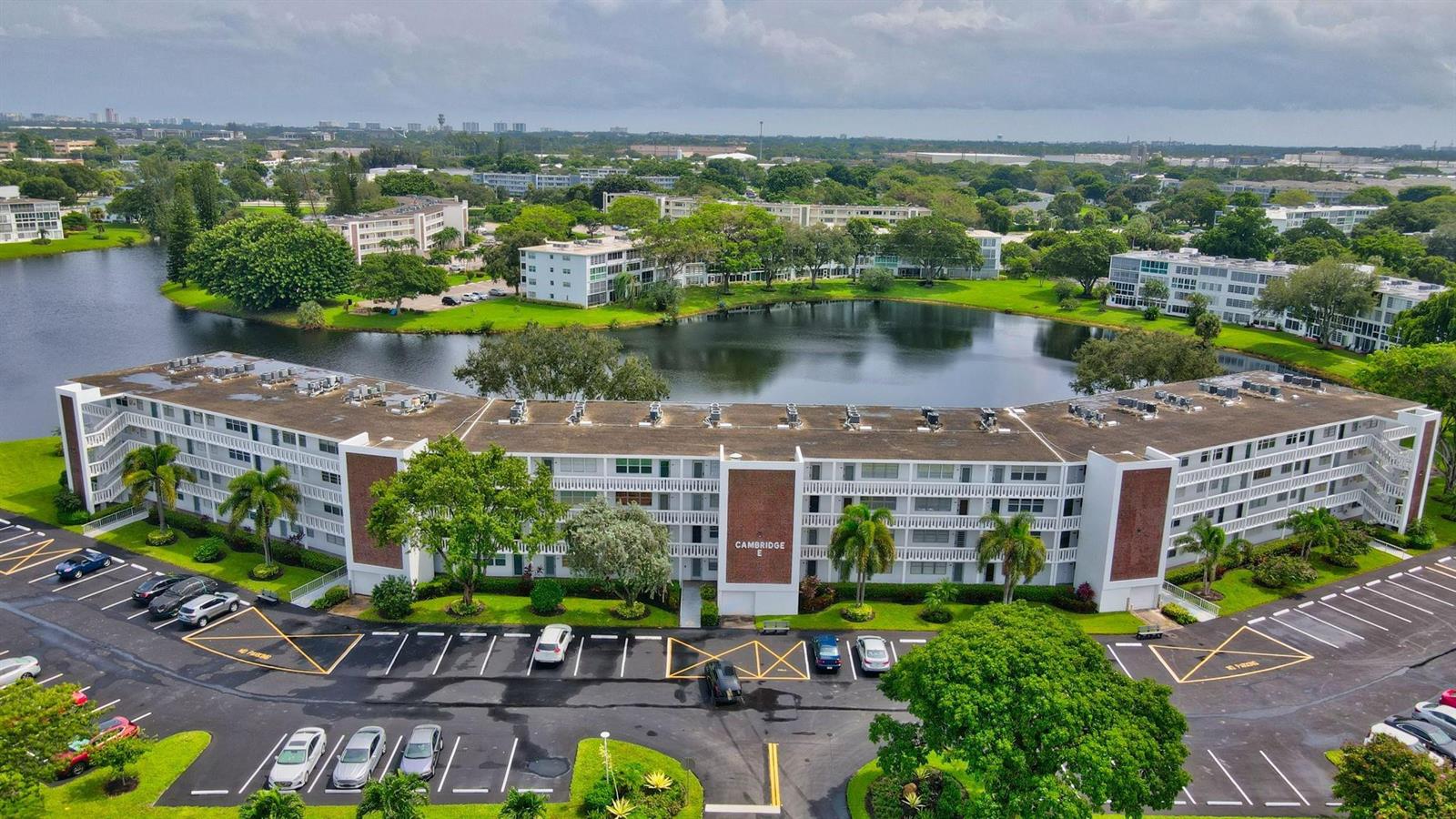 An aerial view of a multi-story apartment building situated next to a lake and parking — 3107 Cambridge # 3107, Deerfield Beach FL 33442, DEERFIELD BEACH, FL