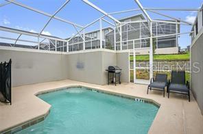 A screened-in patio features a rectangular swimming pool, two lounge chairs, and a grill — 1236 CHALLENGE DRIVE, DAVENPORT, FL