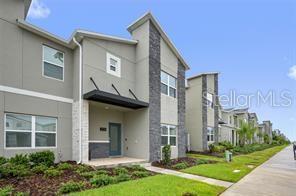 A row of modern townhomes features gray stucco siding, stone accents, and dark metal awnings — 1236 CHALLENGE DRIVE, DAVENPORT, FL
