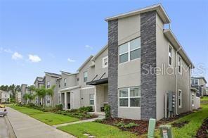 A multi-story townhouse exterior features gray stucco walls, stone veneer accents, and a sidewalk — 1236 CHALLENGE DRIVE, DAVENPORT, FL
