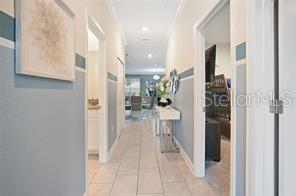 A hallway with light blue walls and tile flooring leads toward an open living area — 1236 CHALLENGE DRIVE, DAVENPORT, FL
