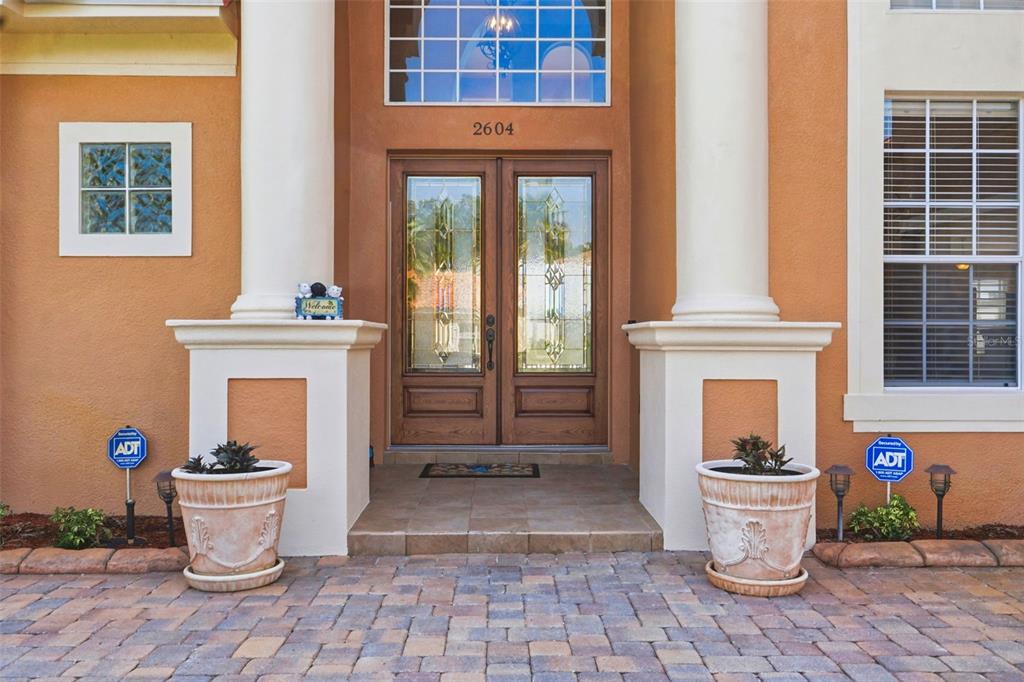 The exterior entrance features double wooden doors, white columns, and two potted plants — 2604 HERITAGE GREEN AVENUE, DAVENPORT, FL