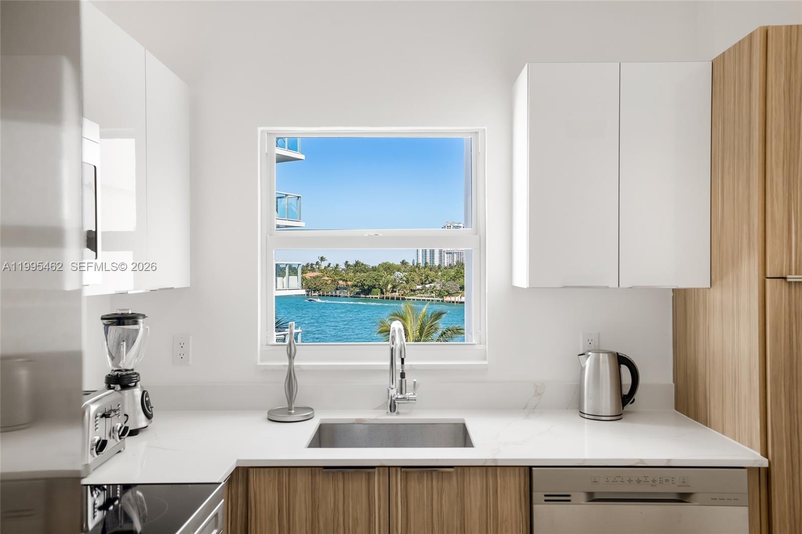 A kitchen features white cabinets, wood-tone lower cabinets, a sink, and a water view — 9881 E Bay Harbor Dr # 504, Bay Harbor Islands FL 33154, BAY HARBOR ISLANDS, FL