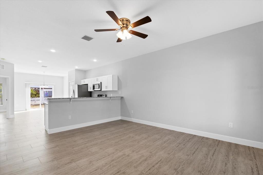 An open-concept living area features light-colored walls, wood-look tile flooring, and a kitchen breakfast bar — 16 TROUT WAY UNIT A & B, POINCIANA, FL