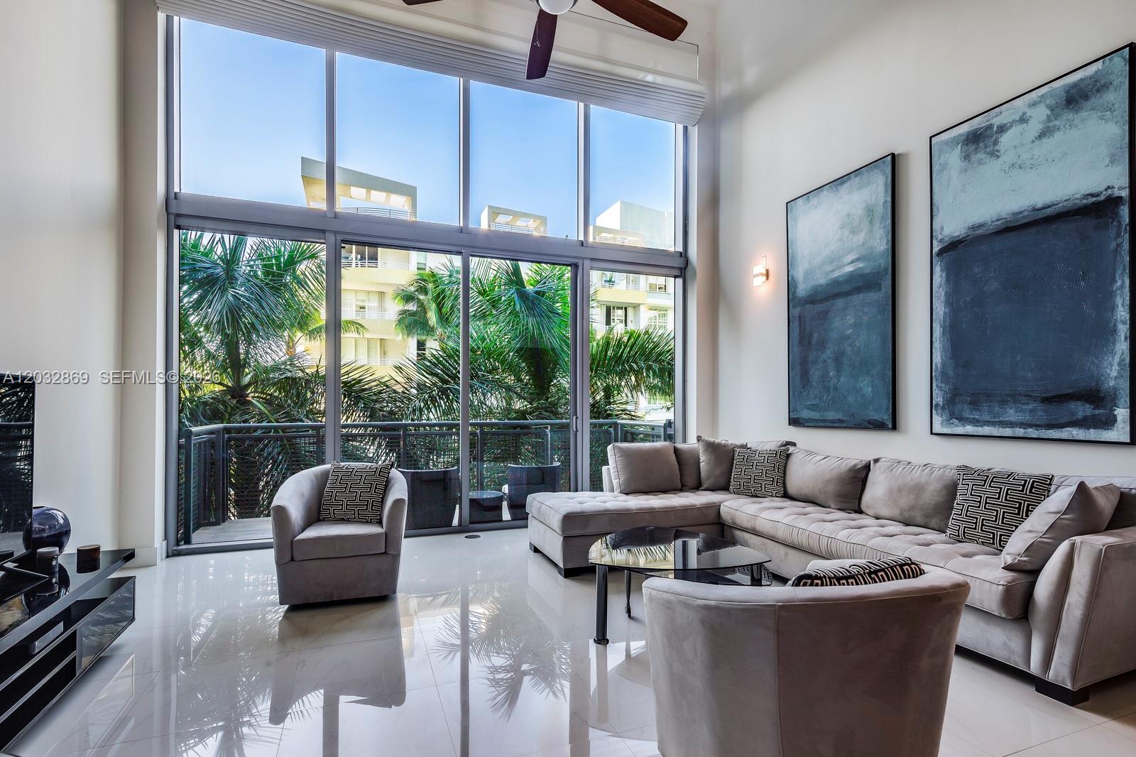 A modern living room features floor-to-ceiling windows, a large sectional sofa, and two abstract paintings — 6000 Collins Ave # 346, Miami Beach FL 33140, MIAMI BEACH, FL