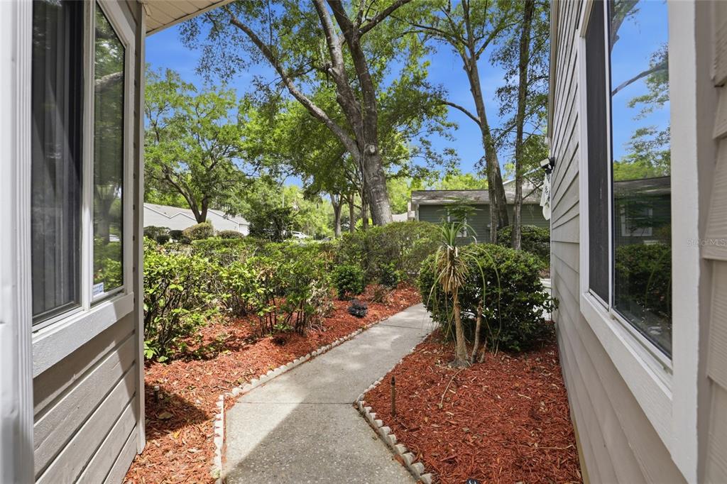 A concrete walkway leads through a landscaped yard between two sections of a house — 829 NW 124TH DRIVE, NEWBERRY, FL