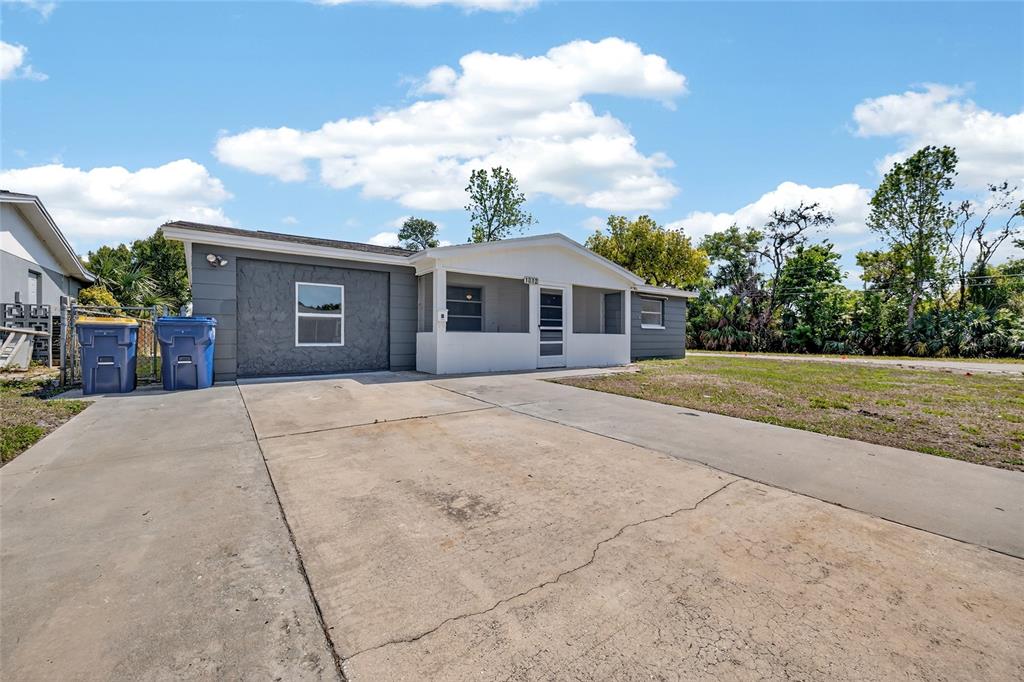 A single-story house with a concrete driveway, a screened-in porch, and a gray exterior — 1012 PRESCOTT LANE, HOLIDAY, FL