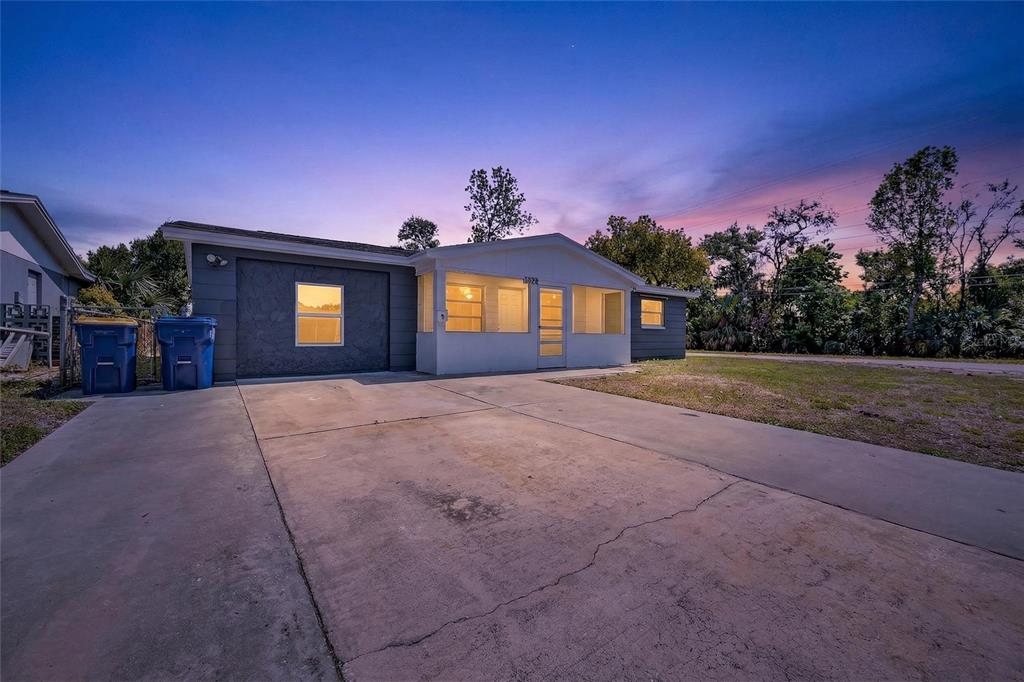A single-story house with a concrete driveway, a screened-in porch, and two blue trash bins — 1012 PRESCOTT LANE, HOLIDAY, FL