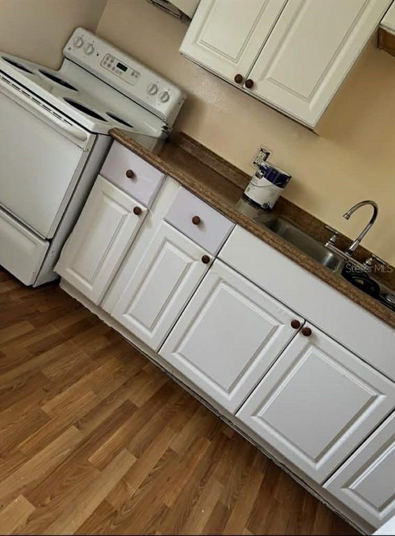 A kitchen features white cabinets, a white electric stove, and a brown laminate countertop — 5885 DAHLIA DRIVE UNIT 30/215, ORLANDO, FL