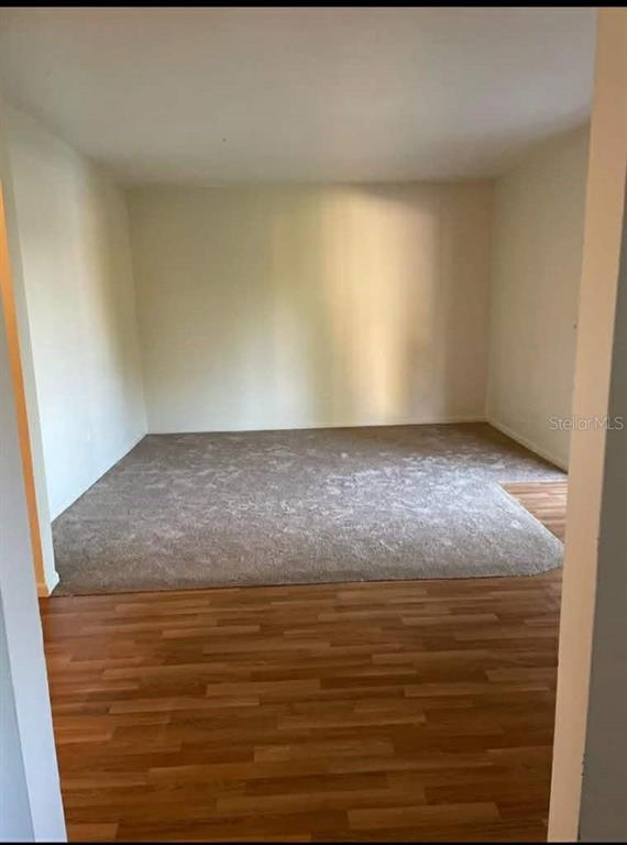 A room with wood-look flooring in the foreground and a carpeted area in the back — 5885 DAHLIA DRIVE UNIT 30/215, ORLANDO, FL