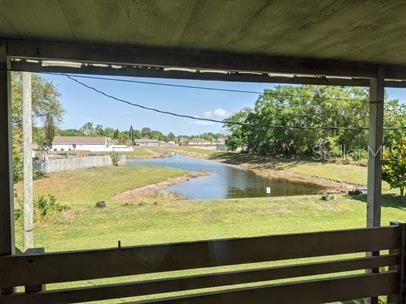 A view of a pond and neighborhood houses from a covered wooden porch — 5885 DAHLIA DRIVE UNIT 30/215, ORLANDO, FL