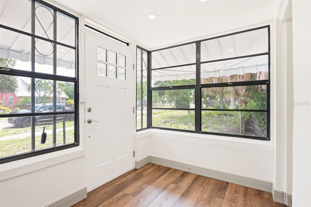 A bright entryway features white walls, wood-look flooring, and large windows with black frames — 517 41ST AVENUE S, ST PETERSBURG, FL