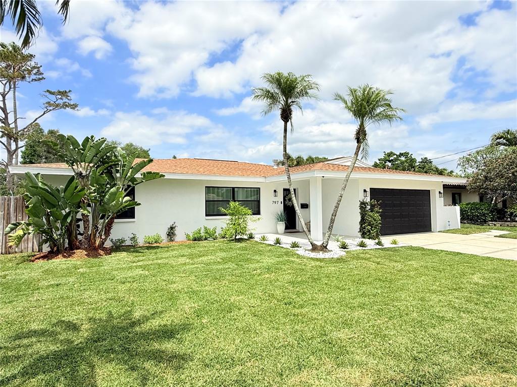A white single-story house with a brown roof, black garage door, and two palm trees — 797 45TH AVENUE NE, ST PETERSBURG, FL