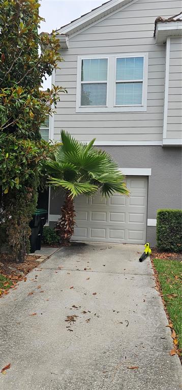 A concrete driveway leads to a garage door beneath a two-story house with gray siding — 9313 SHEPTON STREET, ORLANDO, FL
