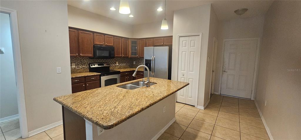 A kitchen features a granite-topped island, stainless steel appliances, and dark wood cabinetry — 9313 SHEPTON STREET, ORLANDO, FL