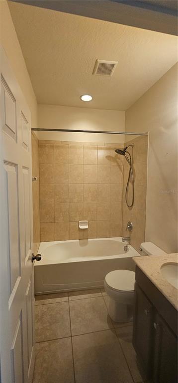A bathroom features a tiled tub-shower combination, a white toilet, and a vanity with countertop — 9313 SHEPTON STREET, ORLANDO, FL