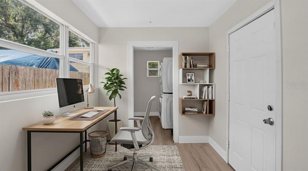 A home office with a desk, chair, and wall-mounted shelving, leading to a laundry area — 2960 EMERSON AVENUE S, ST PETERSBURG, FL