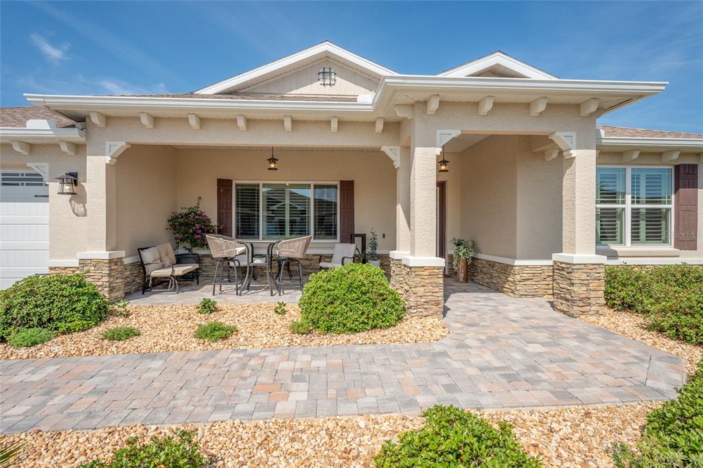 The exterior of a single-story house features a stone-accented porch, a paver walkway, and landscaping — 8250 SW 93RD TERRACE, OCALA, FL
