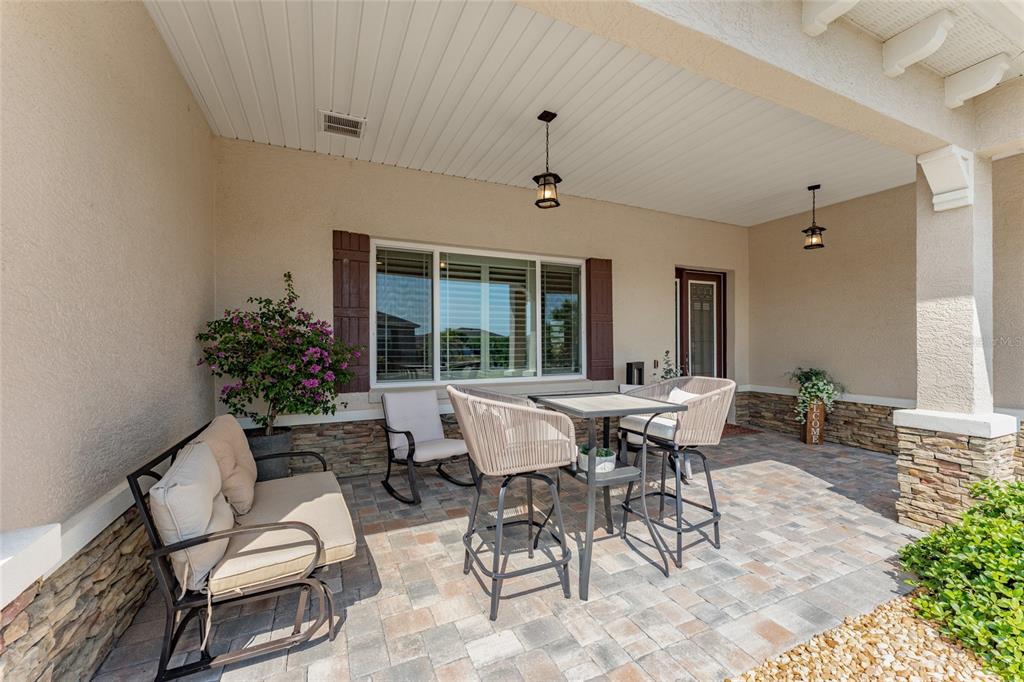 A covered patio features stone accents, a dining set, a bench, and a window — 8250 SW 93RD TERRACE, OCALA, FL