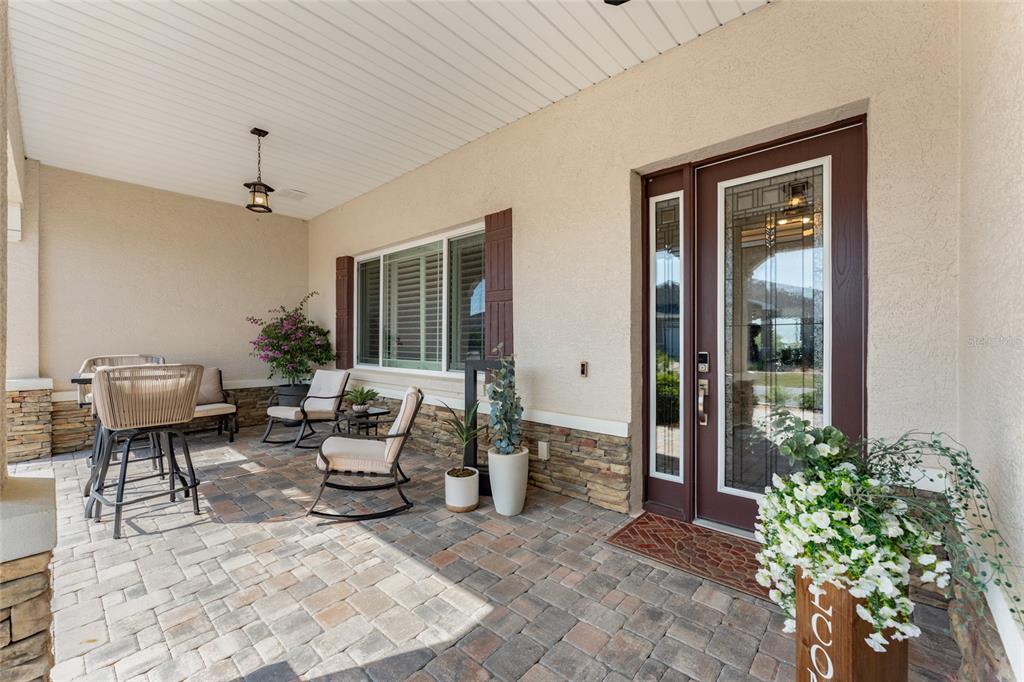 A covered front porch features stone accents, a brown door, and outdoor patio furniture — 8250 SW 93RD TERRACE, OCALA, FL