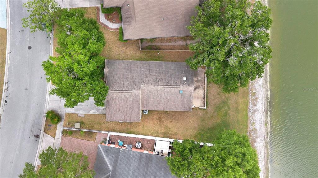 An aerial view shows a house with a brown roof situated between trees and water — 2413 RADNOR AVENUE, ORLANDO, FL