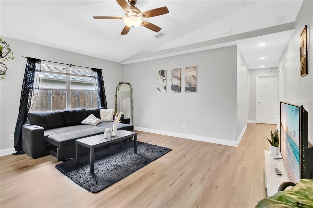 A living room features light wood flooring, a grey sectional sofa, and a ceiling fan — 2413 RADNOR AVENUE, ORLANDO, FL