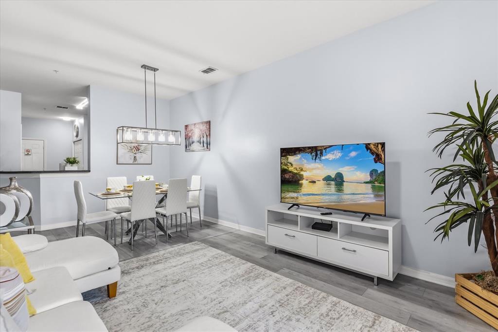 A living and dining area with light gray walls, white furniture, and wood-look flooring — 7525 BLISS WAY, KISSIMMEE, FL